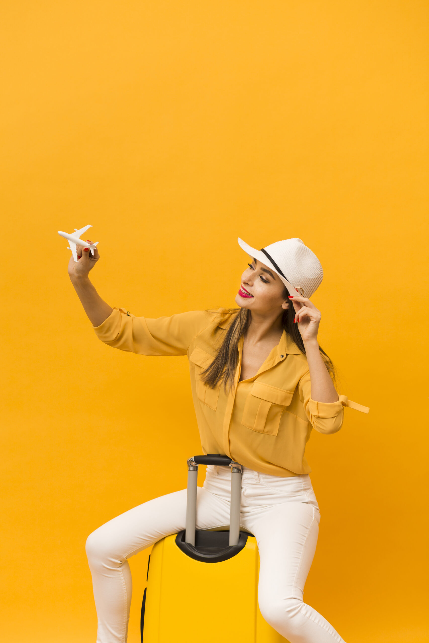 woman-sitting-luggage-holding-plane-figurine